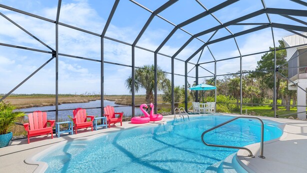 A pool area with a clear view of the surrounding landscape, including a body of water and greenery.
