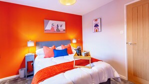 A hotel room with a bed, a nightstand, a lamp, a tray with a cup and a bottle, and a door.