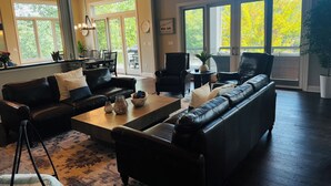 Un salon spacieux avec un grand canapé en cuir noir, une table basse et un coin repas comprenant une table et des chaises.
