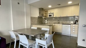 Een kleine keuken met een eettafel en stoelen, een magnetron, een koffiezetapparaat en een vaatwasser.