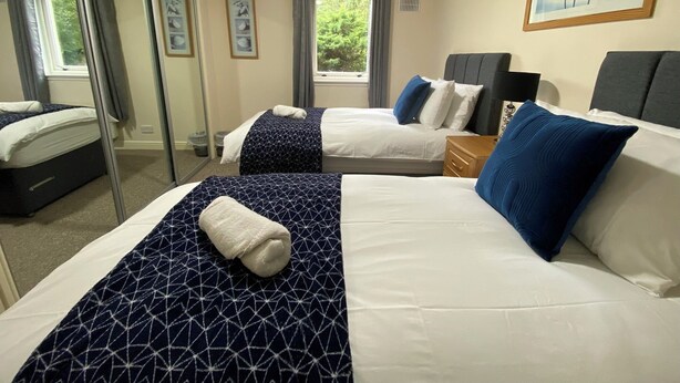 A hotel room with two beds, a large window, and a painting on the wall.
