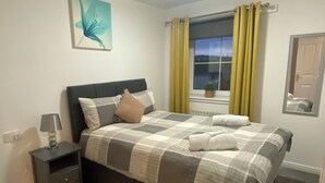 Ein Schlafzimmer mit Bett, Nachttisch und Fenster mit Vorhängen.
