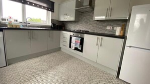 A modern kitchen with white cabinets, a patterned floor, and a window with natural light.