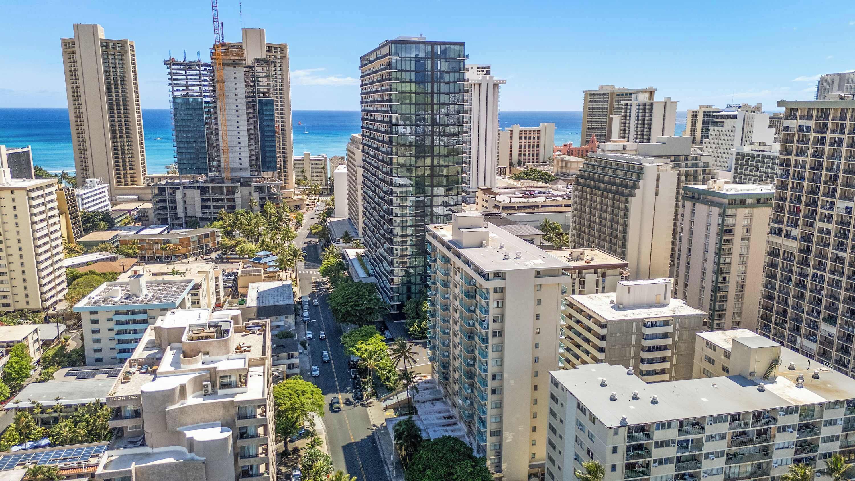 Zona urbana con grattacieli moderni, tra cui un imponente grattacielo in vetro, e vista sul mare.