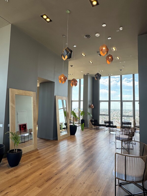 A spacious room with a large window, wooden flooring, and modern pendant lighting.