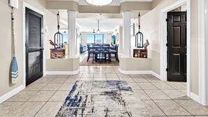 A spacious hallway with a dining area at the end, featuring a large rug, pendant lighting, and decorative birdcages. - 🌊Beach Views-Oversized Balcony-Gulf Front Pool-Hidden Dunes 704🌊 (Panama City Beach)