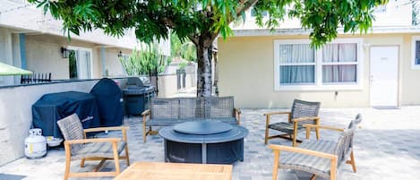 An outdoor patio with wicker furniture, a round table, and a grill.