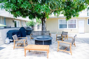 An outdoor patio with wicker furniture, a round table, and a grill.