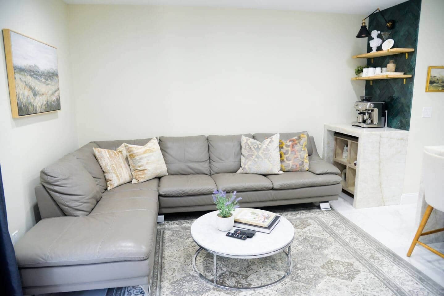 A living room with a grey sectional sofa, a round coffee table, and a patterned rug.