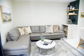 A living room with a grey sectional sofa, a round coffee table, and a patterned rug.