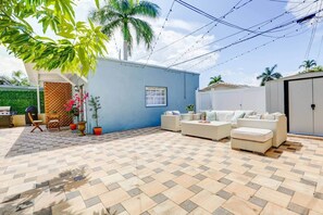 Un patio con mobiliario exterior, una pared azul y una palmera.