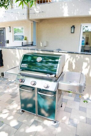 Una parrilla portátil con termómetro digital, quemador lateral y hielera integrada.