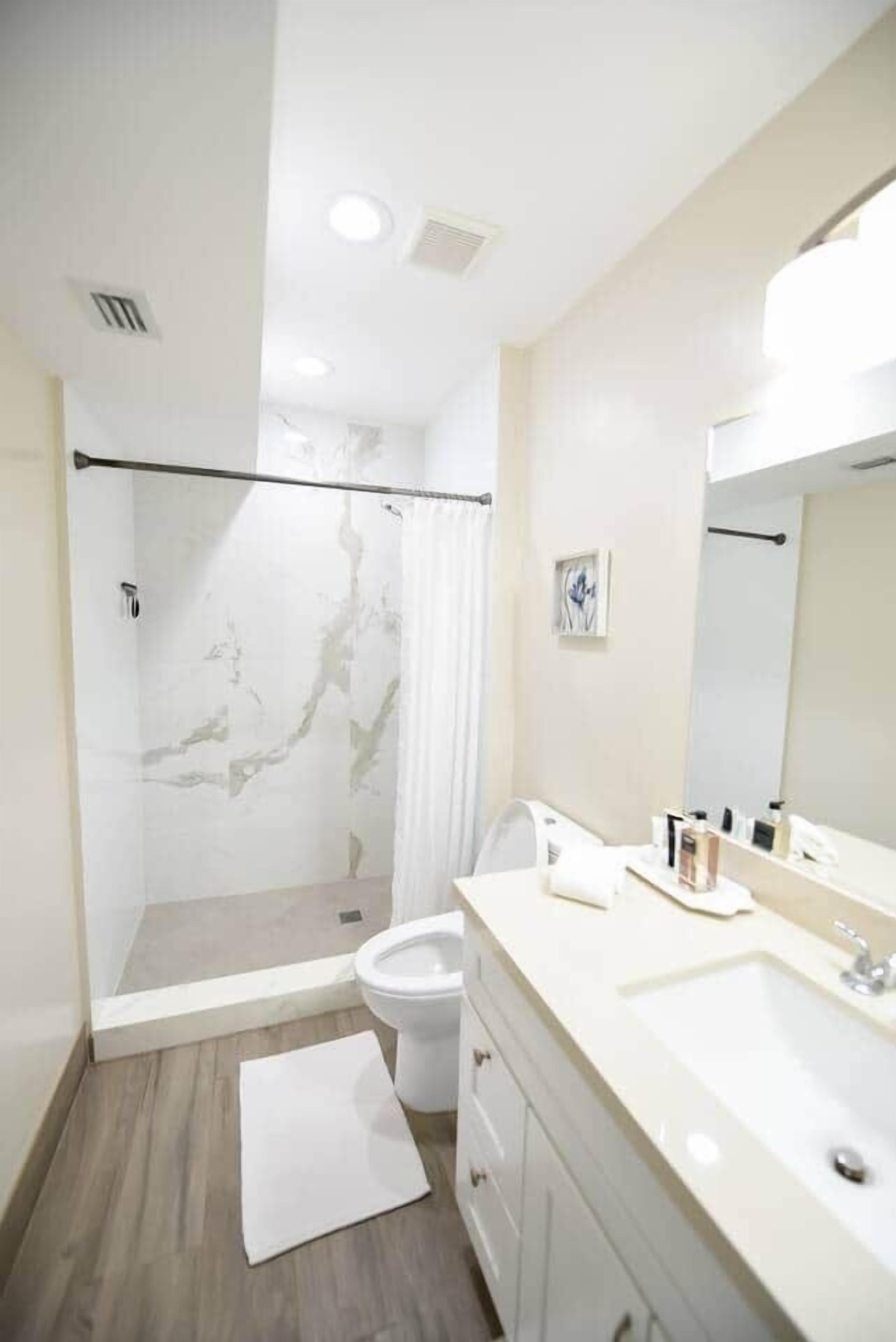 Une salle de bain moderne avec une douche à parois de verre, un lavabo blanc et un grand miroir.