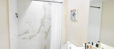 Une salle de bain moderne avec une douche à parois de verre, un lavabo blanc et un grand miroir.