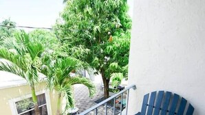 A balcony with a blue chair, a small table, and a potted plant. - The Hamptons Hideaway (Hollywood)