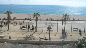 Une plage bordée de palmiers, avec des gens et un ciel dégagé.