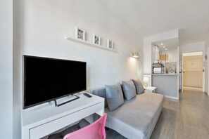 Un salon moderne doté d’un téléviseur à écran plat, d’un canapé et d’un coin repas.