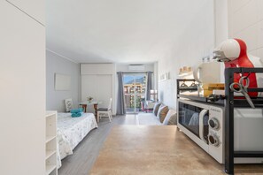 Un espace de vie compact comprenant un coin cuisine, un coin repas et une vue sur l’extérieur, accessible par une porte.