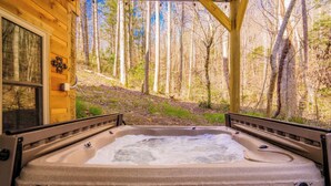Un jacuzzi en una cabaña de madera con vista al bosque.