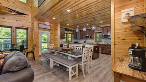 Interior espacioso de una cabaña de madera con comedor, cocina y un letrero que indica un café.