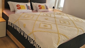 Ein Schlafzimmer mit einer Steinwand, einem Bett mit einem gemusterten Überwurf und zwei Kissen mit dem Wort "smile" darauf.
