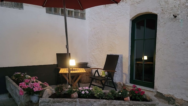 Ein Patio mit Holztisch und Stuhl, einer Lampe und Blumenkästen.