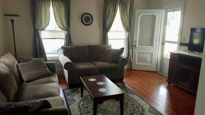 Una sala de estar con un sofá, una mesa de centro, una lámpara y un televisor.