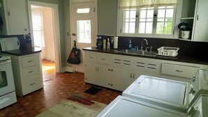 Una cocina con armarios blancos, un lavamanos y un ventanal.