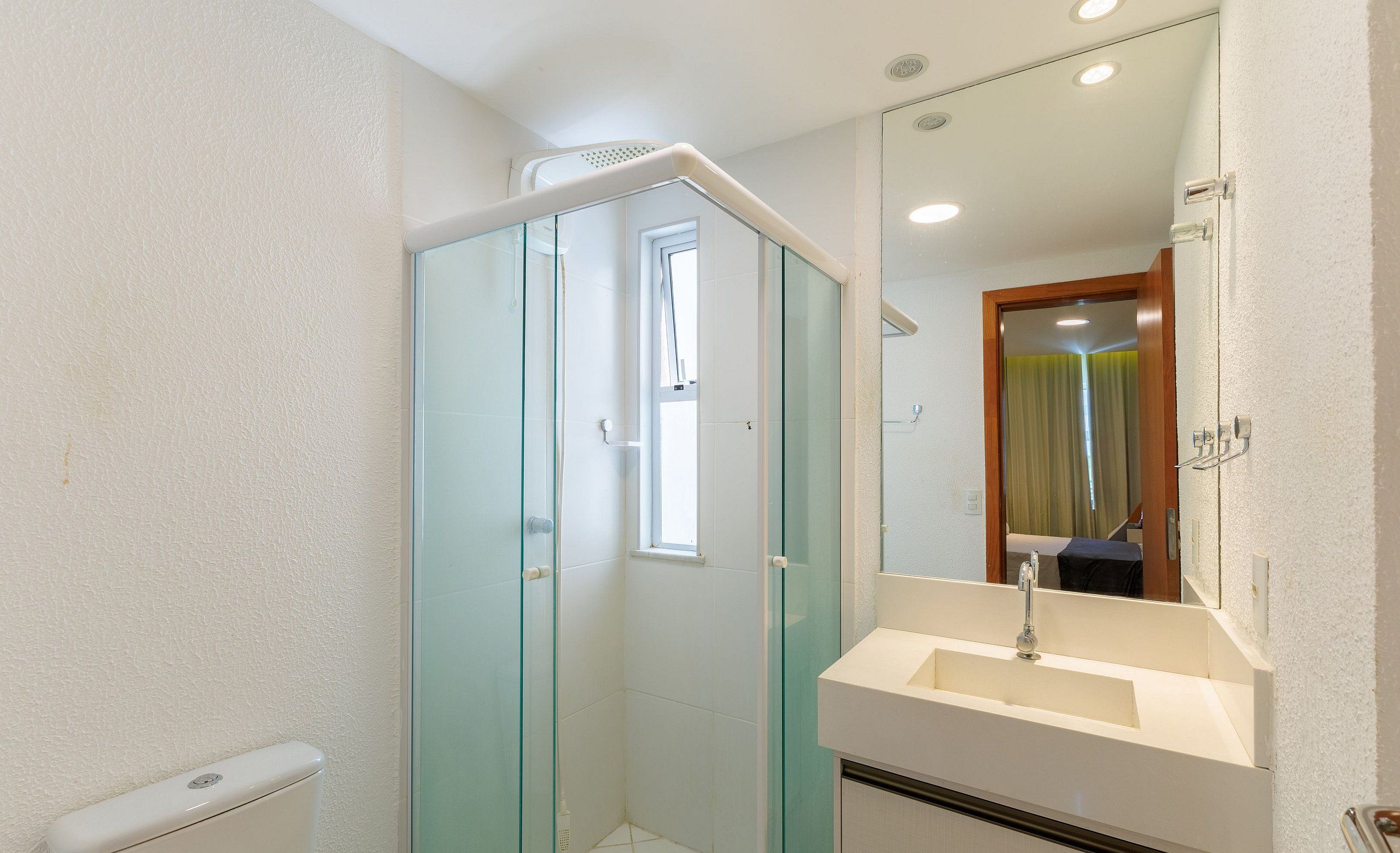 Un baño con cabina de ducha de vidrio, un lavamanos blanco y un espejo sobre él.