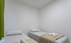 Una habitación con dos camas, cada una con una almohada blanca y una toalla.