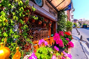 A storefront with a wooden lattice window, potted plants, and a sign above the entrance. - Walnut Shell Hotel Sultanahmet (Istanbul)