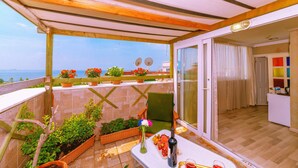 A balcony with potted plants, a table with a bottle and glasses, and a view of the sea. - Walnut Shell Hotel Sultanahmet (Istanbul)