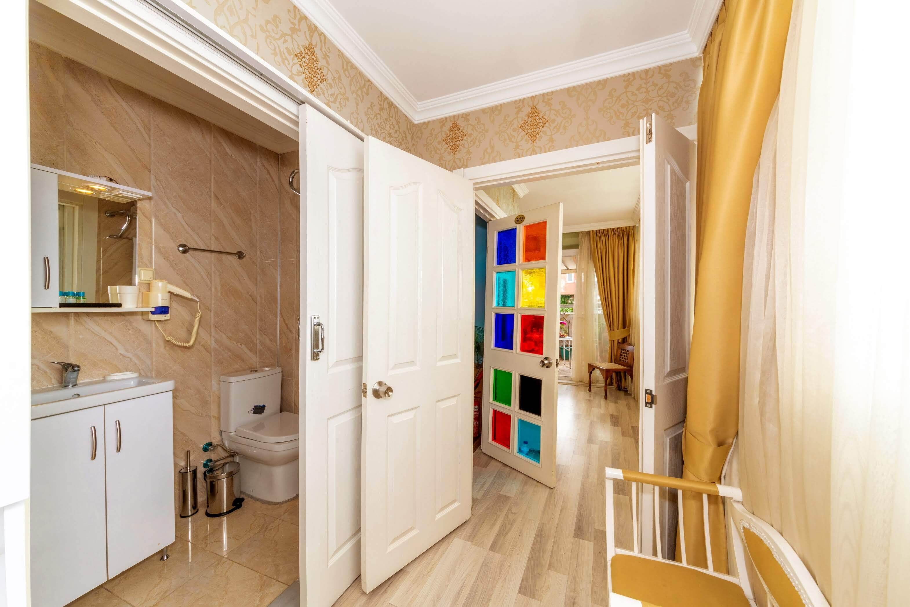 A hotel bathroom with a toilet, sink, and mirror.