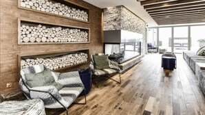 Una sala de estar moderna con pisos de madera, chimenea y estantes empotrados con leña.