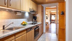 A kitchen with wooden cabinets, a stainless steel sink, and a coffee maker. - Panorama Apartment 2 – NEW! incl. 3 Worlds Card – 140 Free Attractions (Bernau im Schwarzwald)