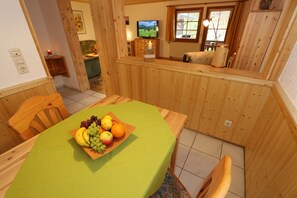 Zona pranzo con tavolo in legno, sedie e una ciotola di frutta.