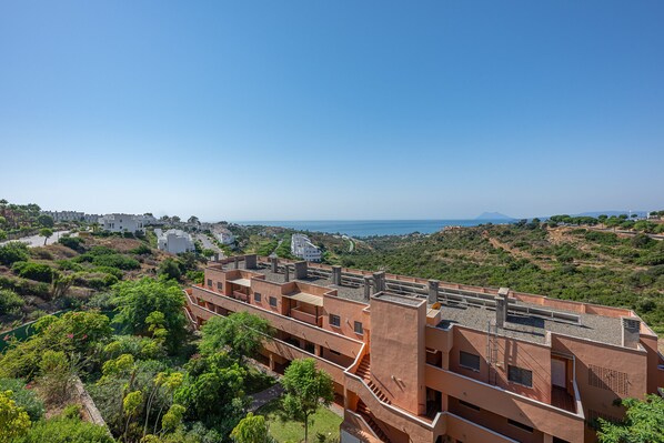 Ein Mehrfamilienhaus, umgeben von Grünflächen, mit freiem Blick auf das Meer.