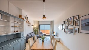 A dining area with a wooden table, chairs, and a view through a large window.