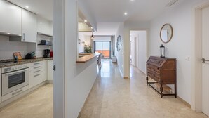 A modern kitchen with white cabinets, a built-in oven, and a countertop with various appliances.
