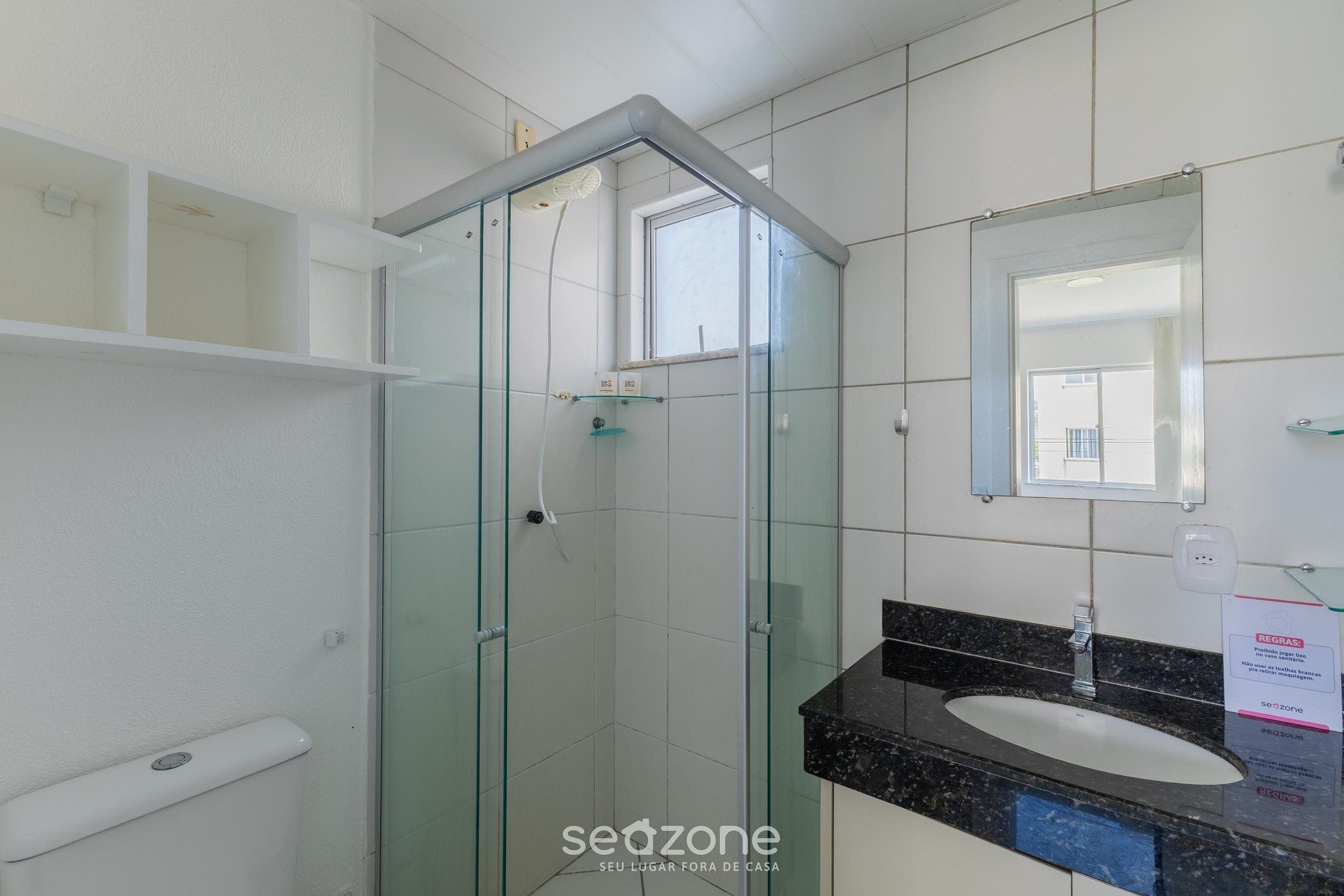A bathroom with a glass-enclosed shower, a white sink, and a mirror above it.