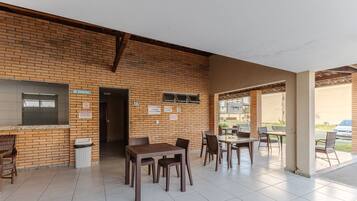 A covered outdoor seating area with brick walls and tiled flooring.