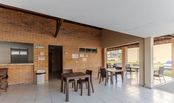 A covered outdoor seating area with brick walls and tiled flooring. - Beautiful apt Less Than 2 min From the sea Vjg0102 (Ilhéus)