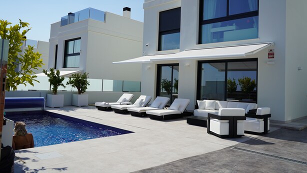 Un área de piscina moderna al aire libre con sillones de descanso y un jacuzzi integrado.