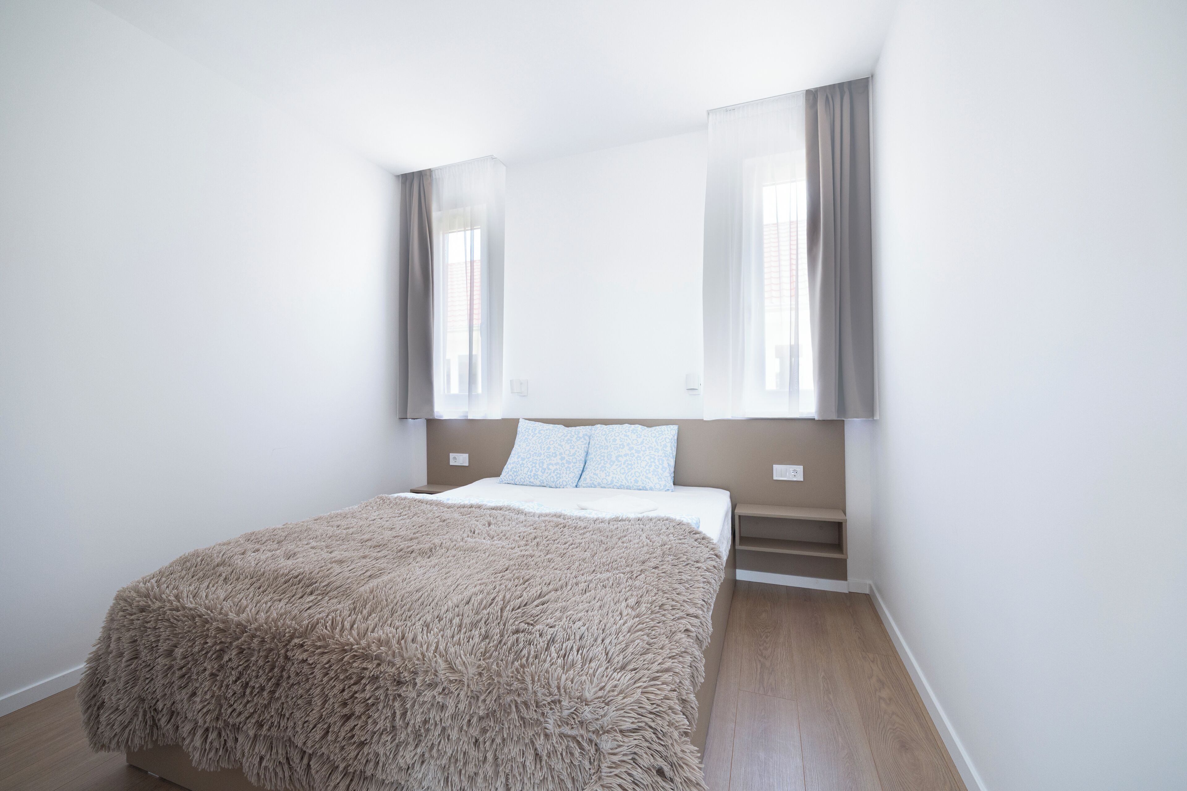 Une chambre à coucher avec un grand lit, une tête de lit et une fenêtre avec des rideaux.
