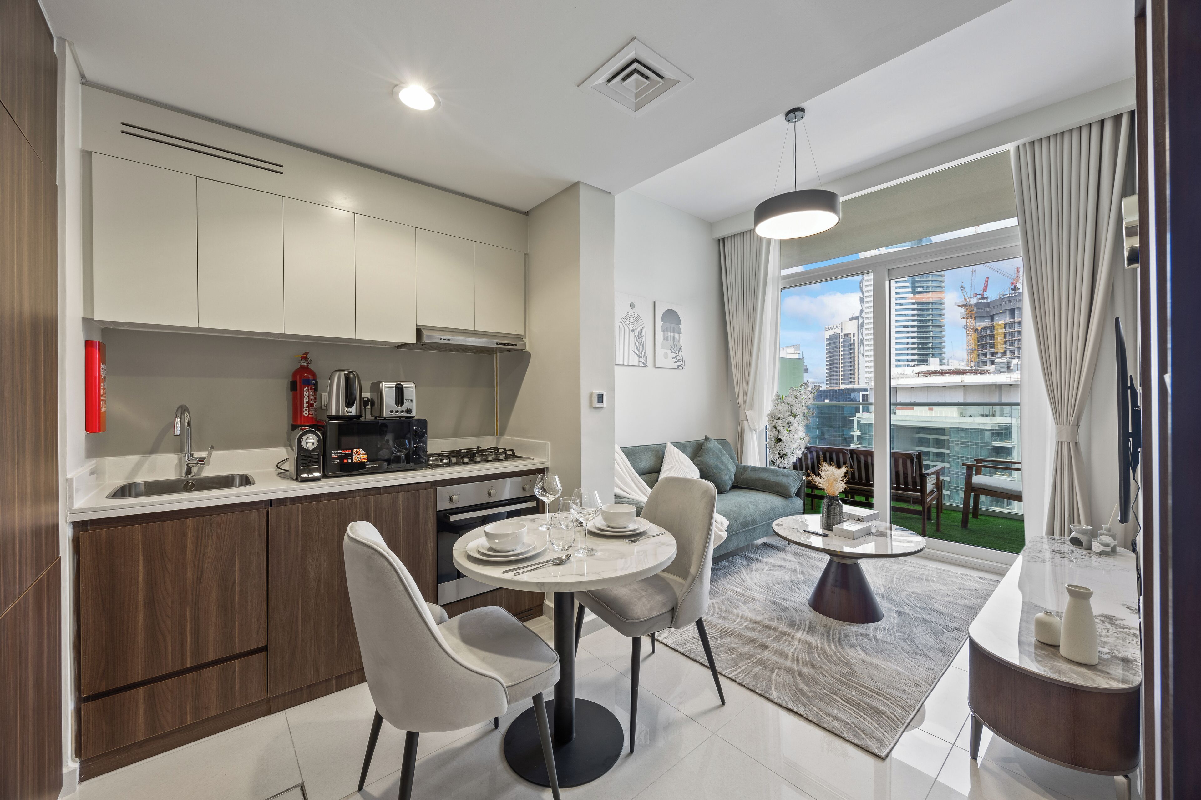 A modern kitchen with a dining area, a view of the city, and a balcony with a view of the construction site.