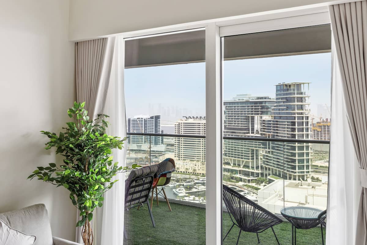 Een balkon met uitzicht op een stadsbeeld, een bloempot en twee stoelen.