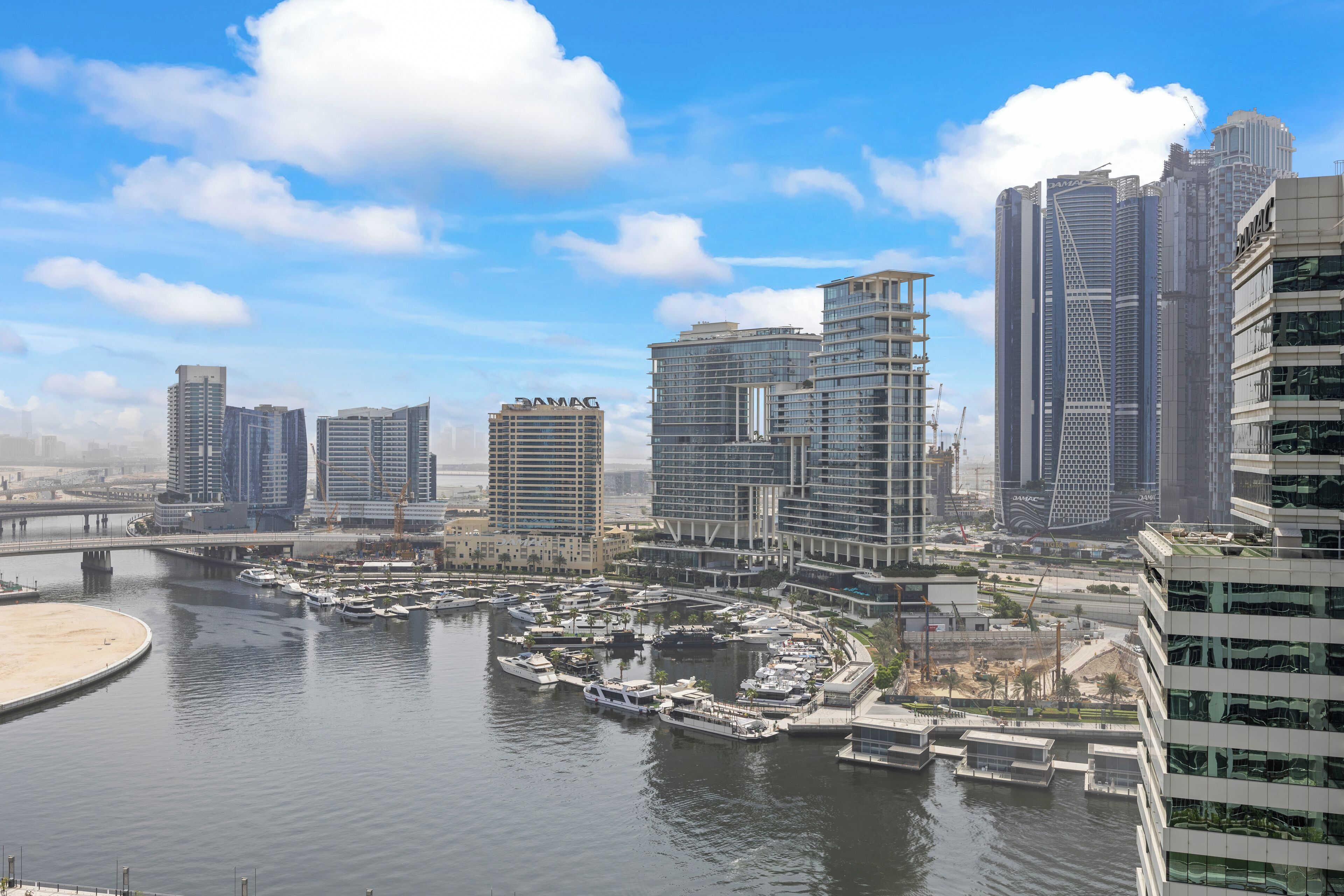Een jachthaven met aangemeerde boten, omgeven door moderne wolkenkrabbers.