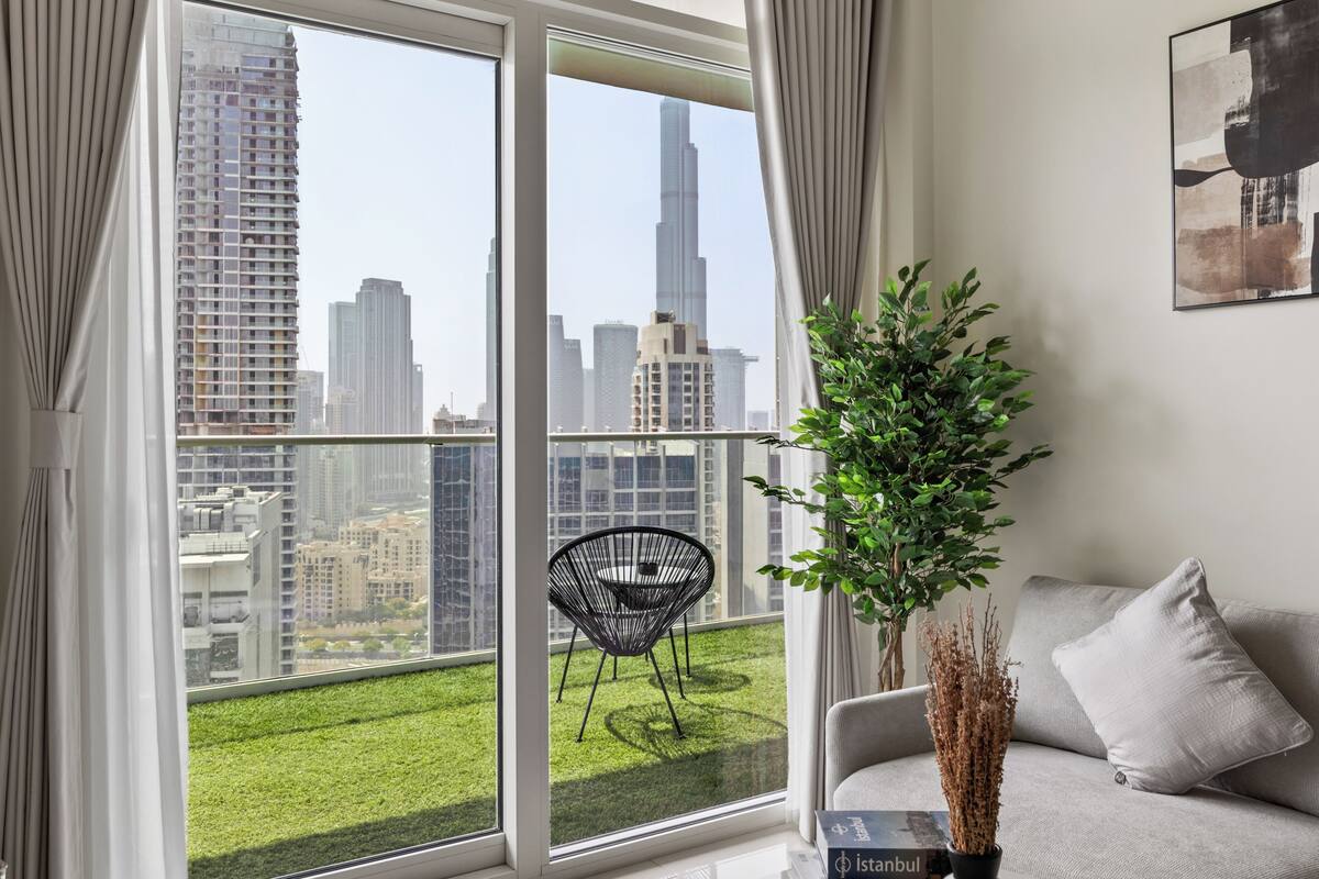 Een moderne woonkamer met een groot raam dat uitzicht biedt op een stadsgezicht, inclusief een opvallend wolkenkrabber.