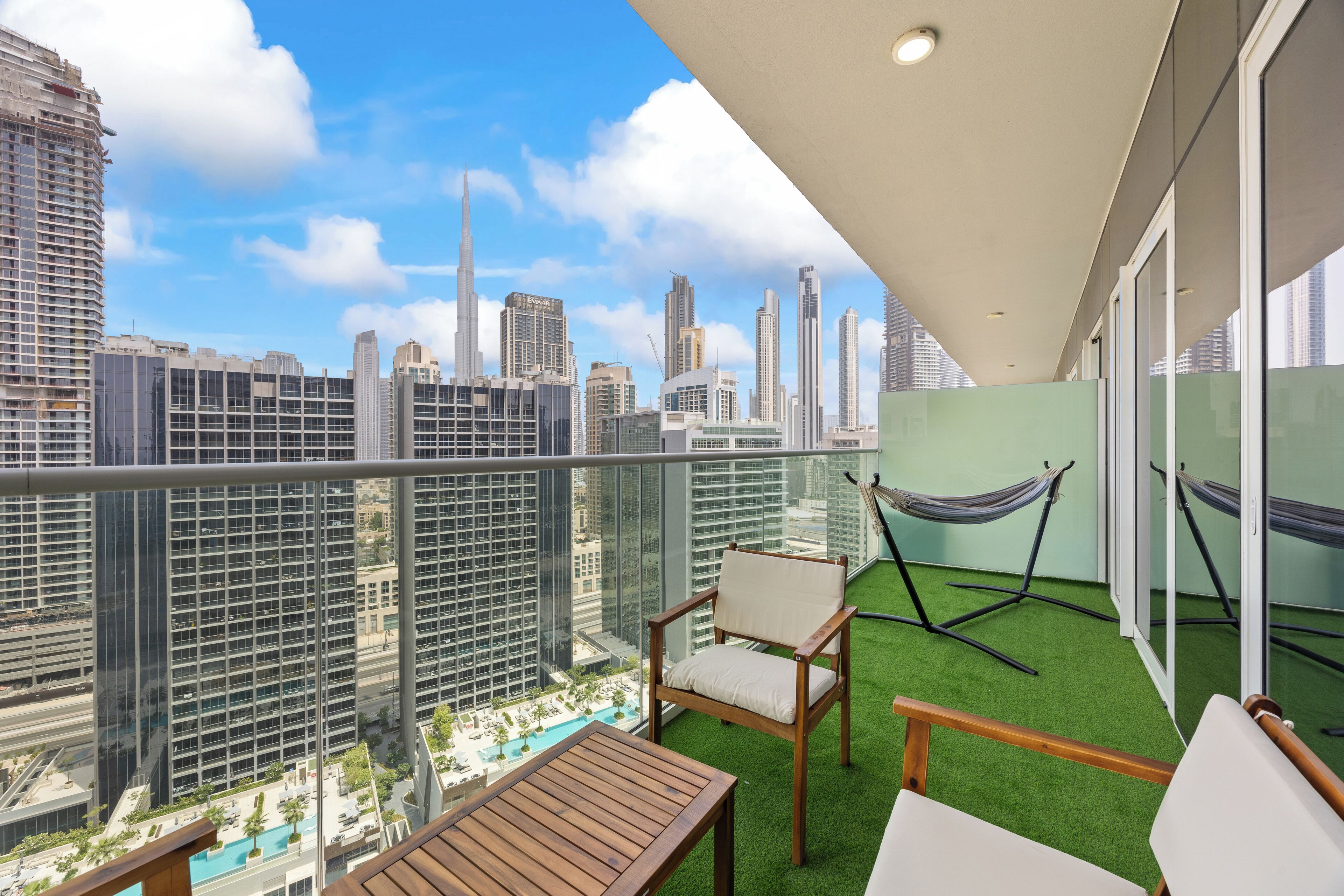 A balcony with a view of a city skyline, a hammock, and a pool.