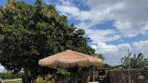 A swimming pool with a stone border, surrounded by a patio area with wicker furniture and a thatched umbrella. - appartement,calme,securise entre mer et campagne (Juan Dolio)